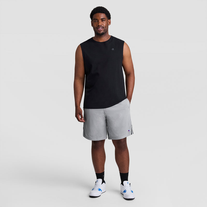 A man smiles in Champion 10" Lacrosse Mesh Shorts - Big & Tall (light gray), a sleeveless black shirt, black socks, and white sneakers, standing against a plain light gray background.
