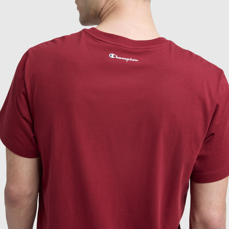 A person is seen from the back wearing a Champion Classic Graphic T-Shirt, Script Logo, in red, with the iconic logo near the neckline—ideal for casual streetwear style.