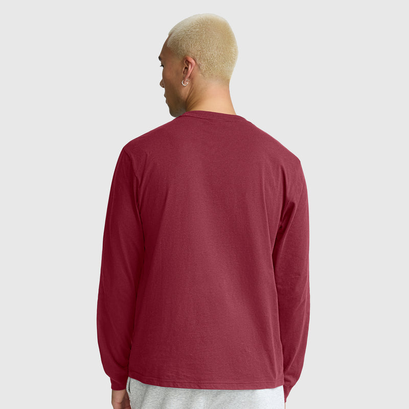 A person with short blond hair is shown from behind, wearing a Champion Classic Long Sleeve T-Shirt with an embroidered C logo in maroon and light gray pants against a plain light gray background.