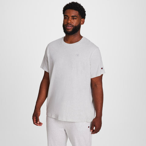 A man with short curly hair and a beard models the Champion Classic T-Shirt, C Logo - Big & Tall, paired with matching sweatpants against a plain white background, looking slightly to the side with a relaxed expression.