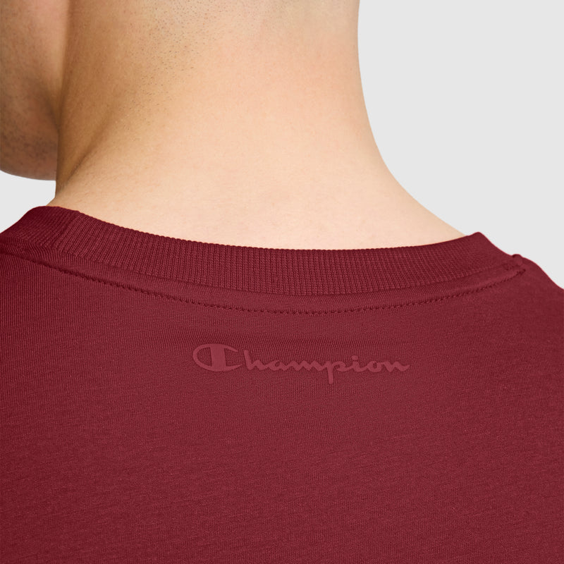 Close-up of the back of a person’s neck and shoulders wearing Champion’s Classic T-Shirt, C Logo in maroon, featuring the tonal Champion logo near the collar.