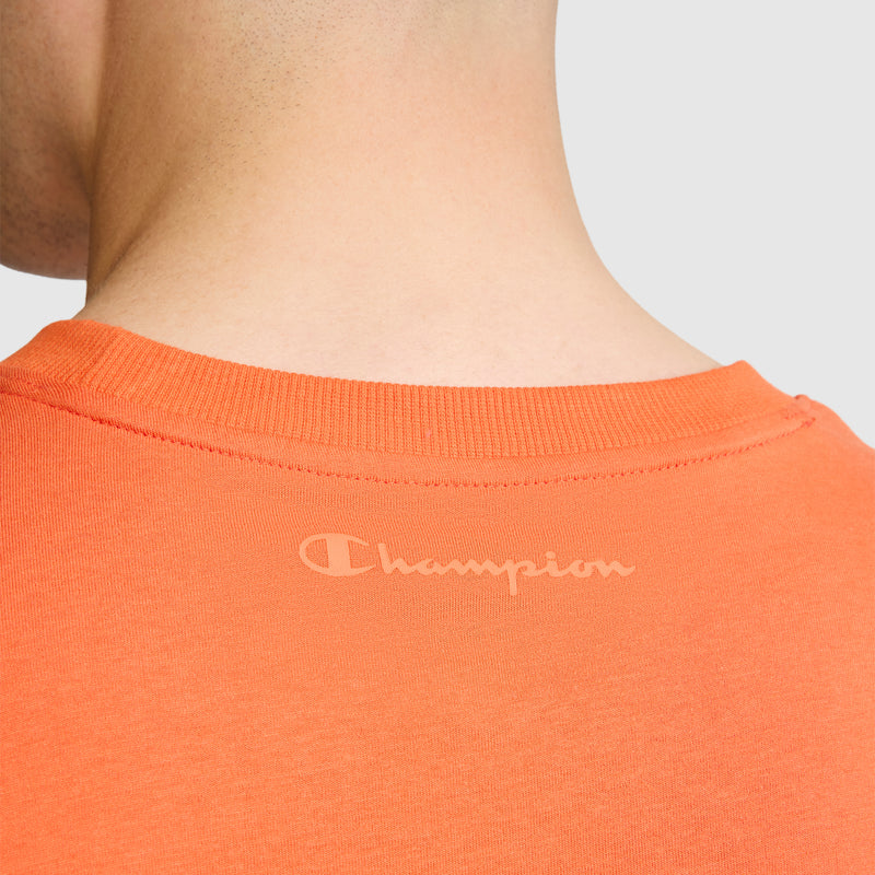 Close-up of the back of a person's neck and shoulders wearing the Champion Classic T-Shirt, C Logo in orange, featuring the iconic Champion logo printed below the collar and crafted from soft cotton fabric for all-day comfort.
