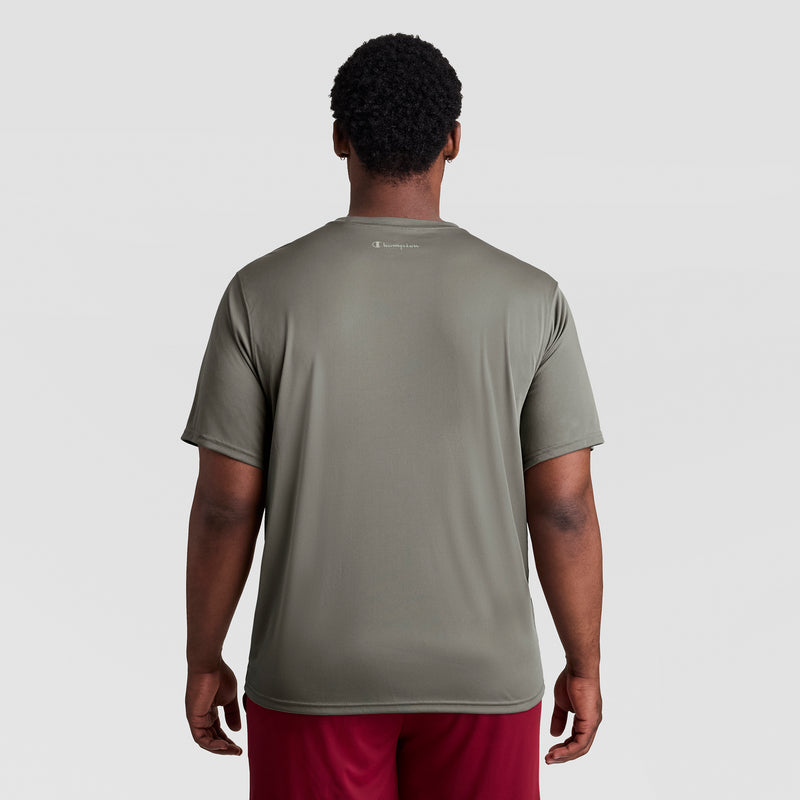 A man faces away, wearing a loose-fitting olive Champion Sport T-Shirt with a reflective C logo (Big & Tall) and red shorts against a plain light gray background.