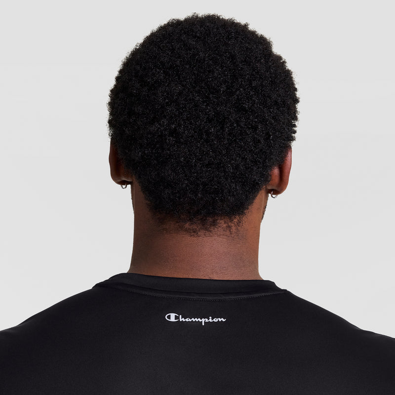 A person with short, curly black hair is seen from behind wearing a Champion Sport Muscle Tank, Reflective C Logo - Big & Tall in black. "Champion" is printed in white below the collar against a plain light background.