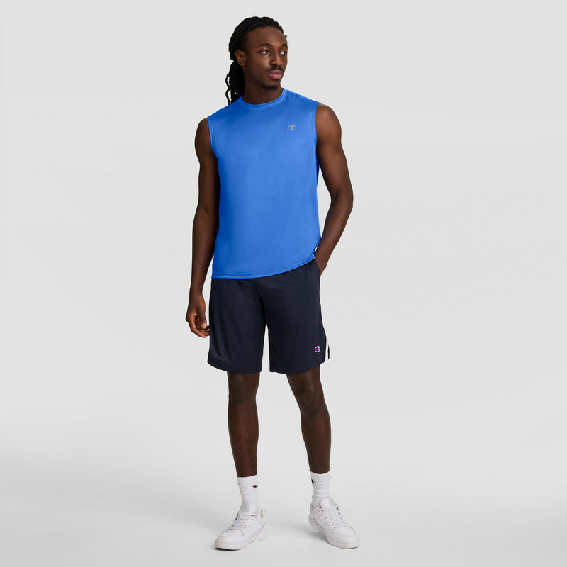 A man stands against a plain background wearing the Champion Sport Muscle Tank with a Reflective C Logo, navy shorts, white socks, and white sneakers. He looks slightly to the side with one hand relaxed by his hip.