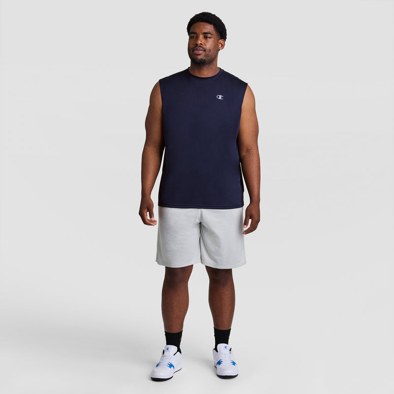 A man faces forward against a plain light background, wearing the Champion Sport Muscle Tank with Reflective C Logo (Big & Tall), light gray shorts, black socks, and white sneakers. He has a relaxed expression and posture.