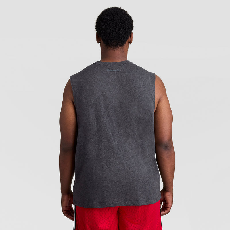 A man with short curly hair is seen from the back, wearing a Champion Big & Tall Muscle Tank (C Logo) in dark gray, paired with red shorts, standing against a plain light background.