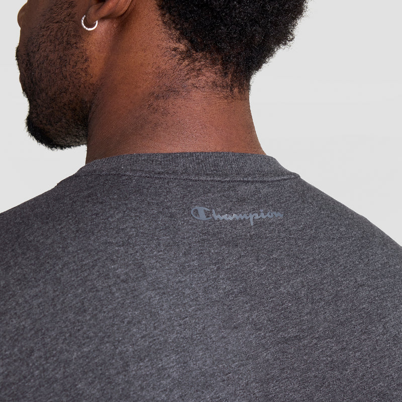 Back view of a person wearing the Champion Muscle Tank, C Logo - Big & Tall in dark gray, featuring "Champion" in light gray lettering on the upper back. The individual has short hair and wears a small hoop earring.