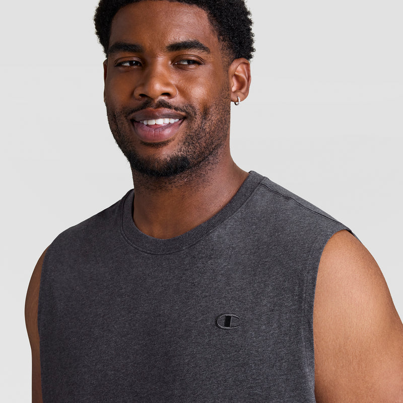 A man with short curly hair, a trimmed beard, and a small hoop earring smiles while wearing the Champion Muscle Tank, C Logo - Big & Tall in dark gray against a plain light gray background.