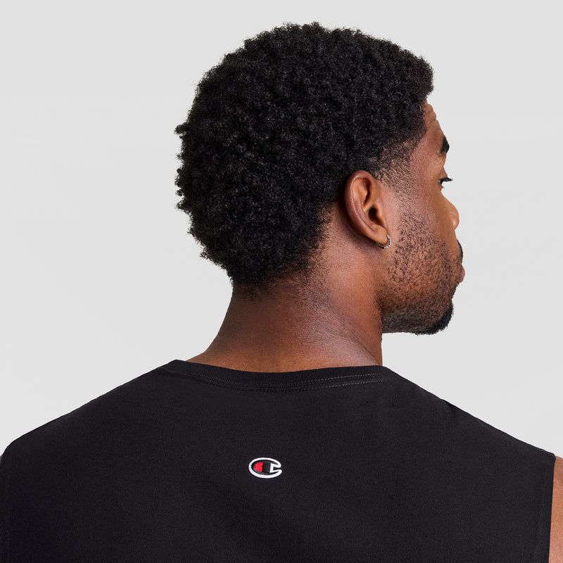 A man with short curly hair is shown from behind, wearing a black Champion Muscle Tank, C Logo - Big & Tall. The Champion logo appears on the back, and the background is plain and light-colored.