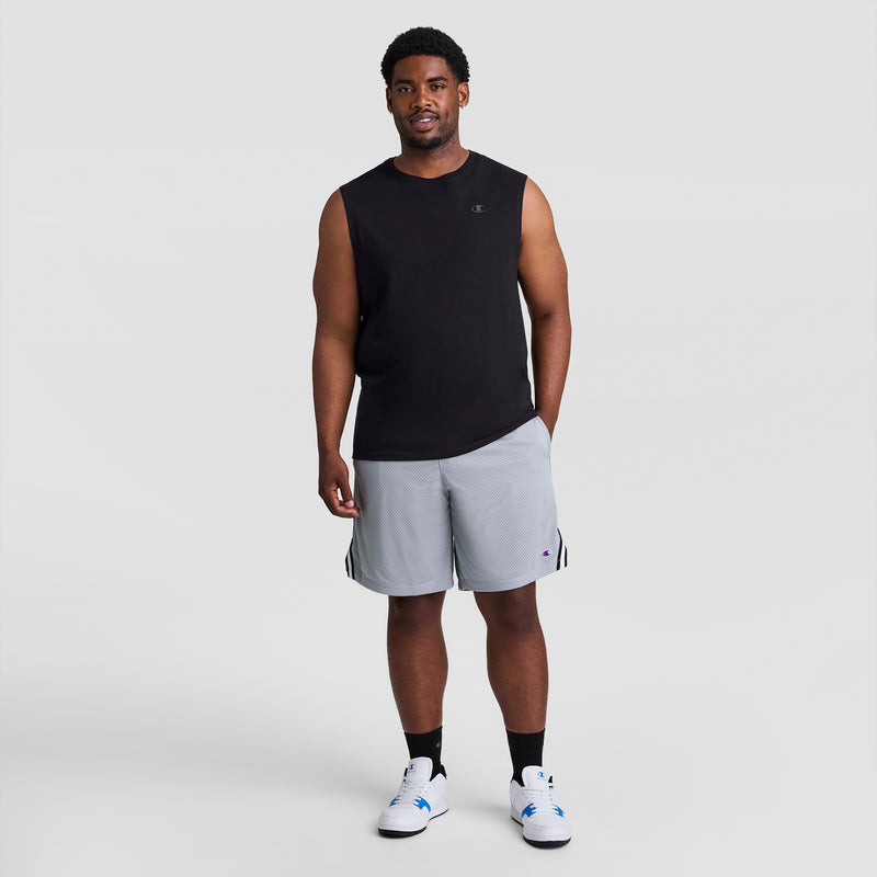 A man faces forward against a plain light gray background, wearing the Champion Muscle Tank, C Logo - Big & Tall in black, light gray athletic shorts, black socks, and white sneakers.