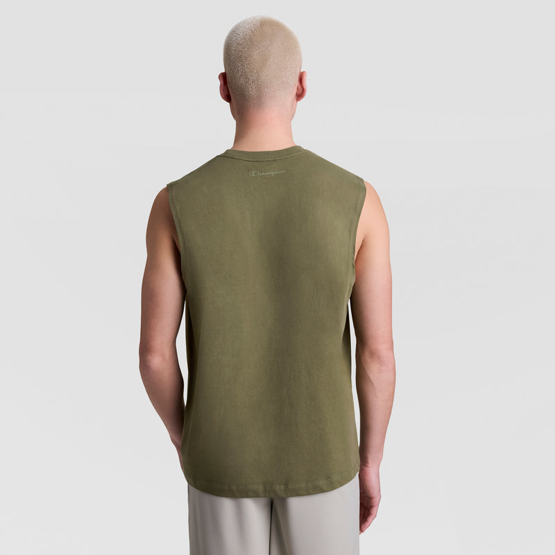 A person with short, bleached blond hair faces away, wearing a Champion Muscle Tank, C Logo in olive green and light gray pants against a plain light gray background.