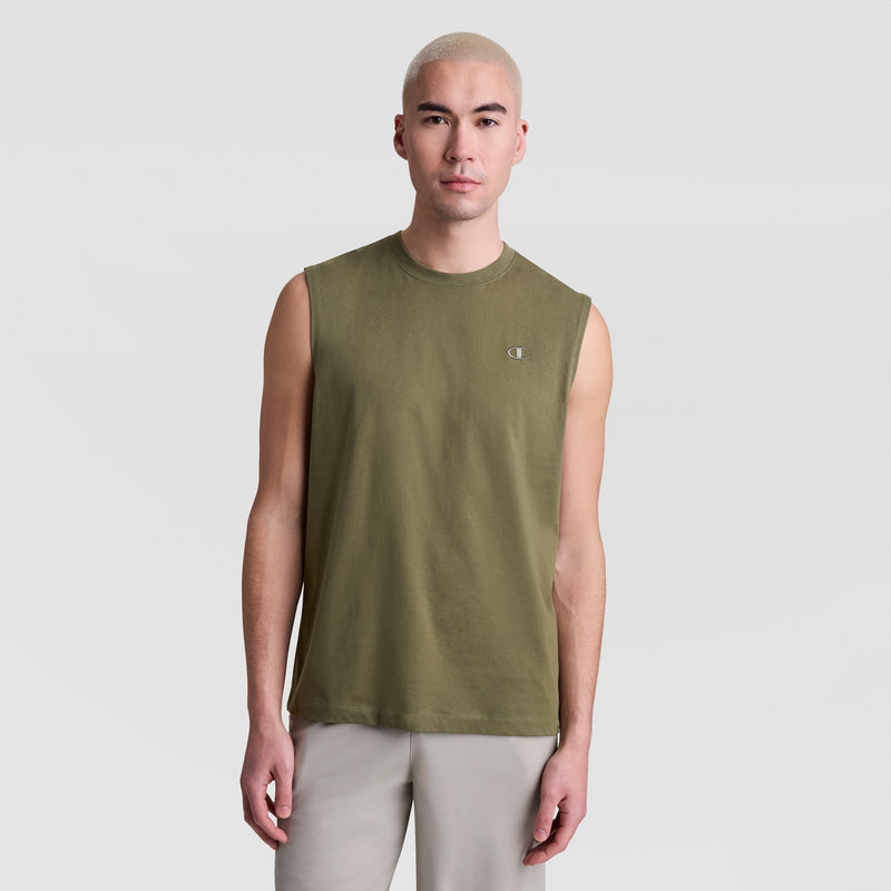 A person with short, light blonde hair wears a Champion Muscle Tank, C Logo in olive green and light gray pants, standing against a plain light gray background.