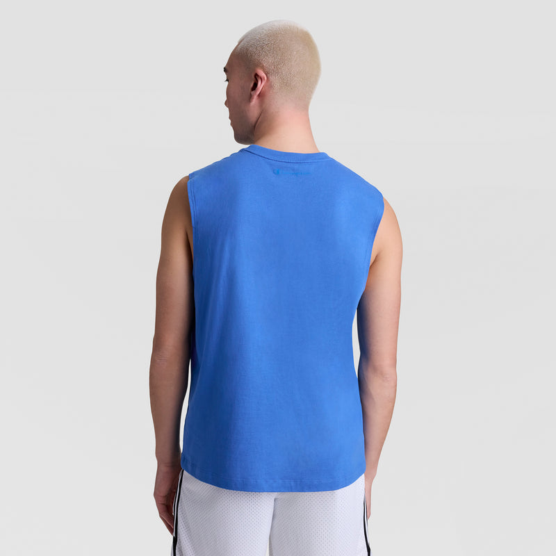 A person with short blonde hair, wearing a Champion Muscle Tank, C Logo in blue and white shorts with black stripes, stands facing away against a plain light gray background.