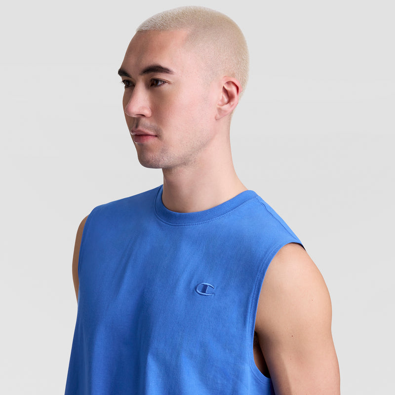 A person with short, bleached blond hair wears a Champion Muscle Tank with a small C logo on the chest, looking to the side against a plain light gray background.