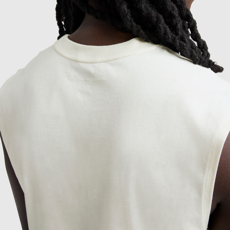 A close-up of a dark-skinned person with long, twisted hair wearing a Champion Muscle Tank, C Logo. The sleeveless off-white top features the embroidered Champion logo on the upper back near the neckline.