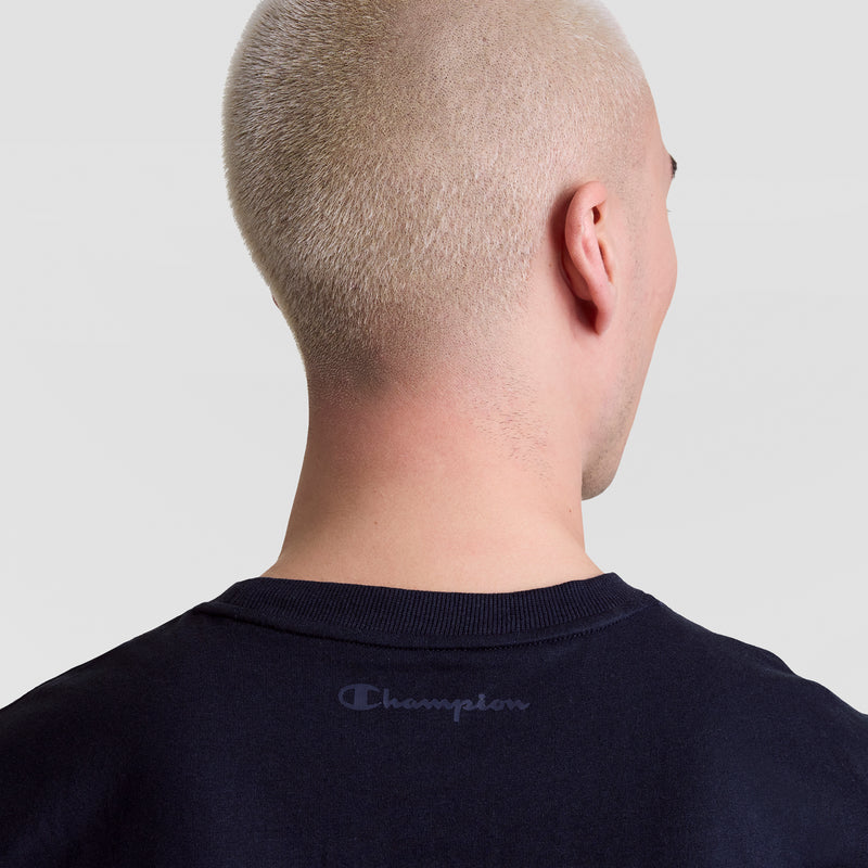 A person with very short, platinum blonde hair is shown from behind, wearing a dark navy Champion Muscle Tank, C Logo. "Champion" is printed on the upper back. The background is plain and light gray.