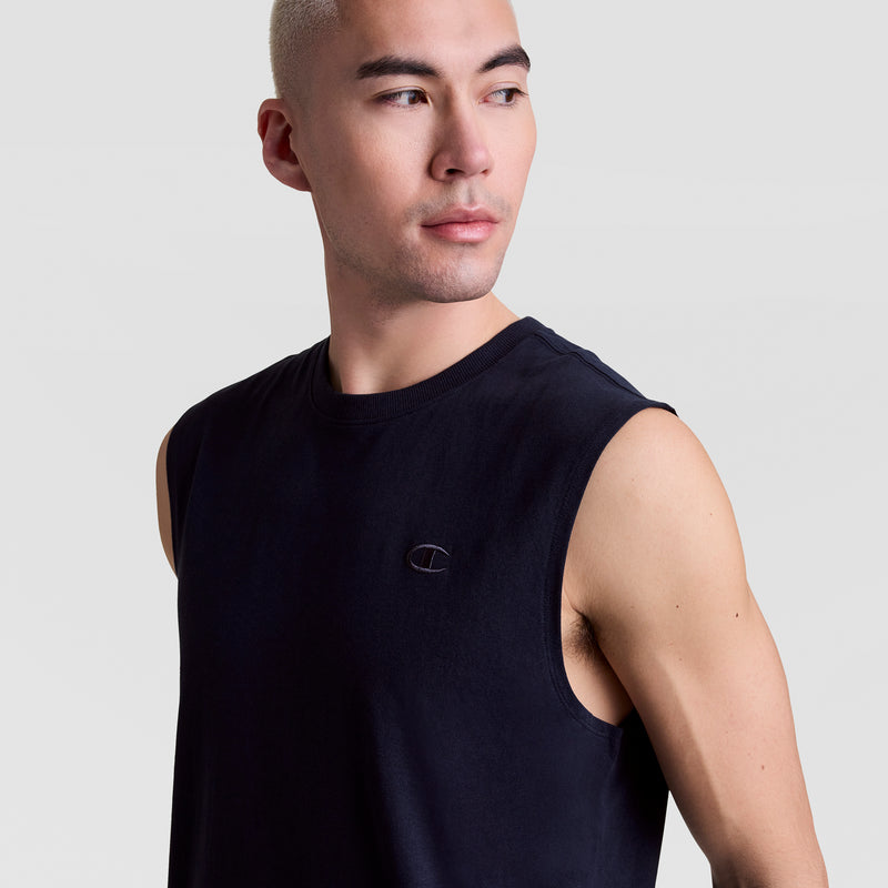 A person with short, light hair models the Champion Muscle Tank, C Logo—a sleek black muscle tee with a small embroidered logo on the chest—looking to the side against a plain light gray background.