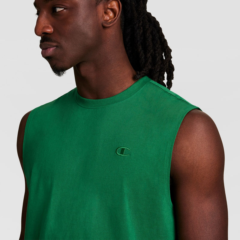 A man with long dreadlocks wears the Champion Muscle Tank featuring a small embroidered C logo on the chest, looking to the side against a plain background.