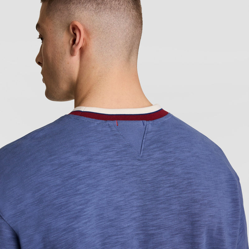 A man with short hair is shown from behind wearing a Champion Modern Retro Washed Crew Sweatshirt with a C Logo and maroon and white-trimmed collar, set against a plain light background.