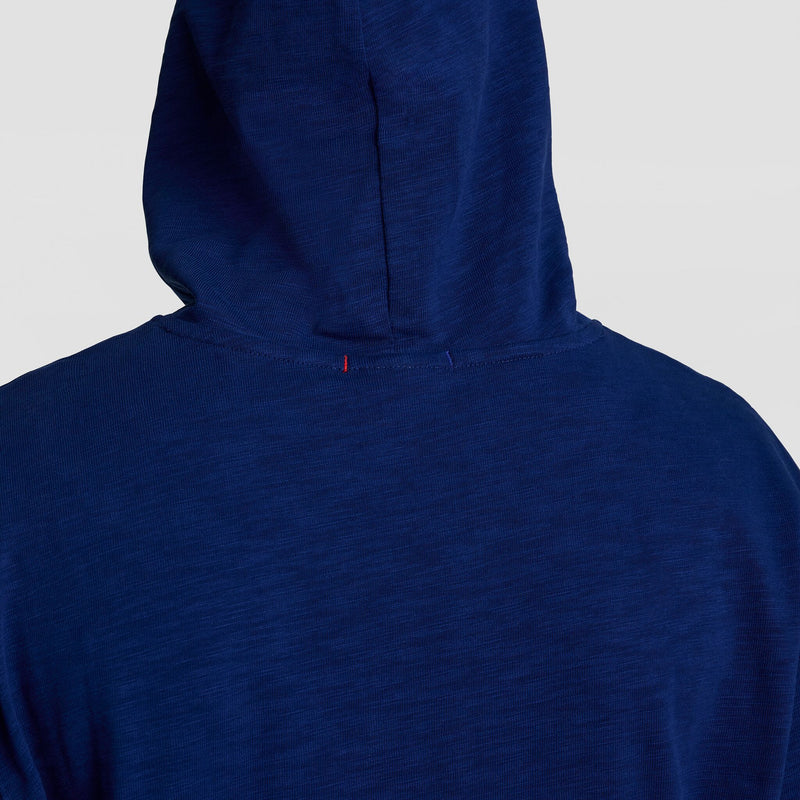A close-up of the back of the Champion Modern Retro Washed Hoodie in blue, featuring a hood up and a small red stitch by the neckline. The plain, light background highlights the classic C Logo style.
