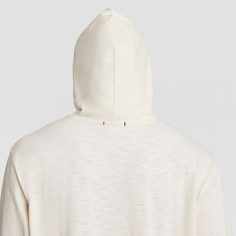 A person is seen from the back wearing the Champion Modern Retro Washed Hoodie, C Logo, with the hood up. Small red and blue stitches appear near the neckline, and the soft, textured fabric gives a vintage-inspired look.