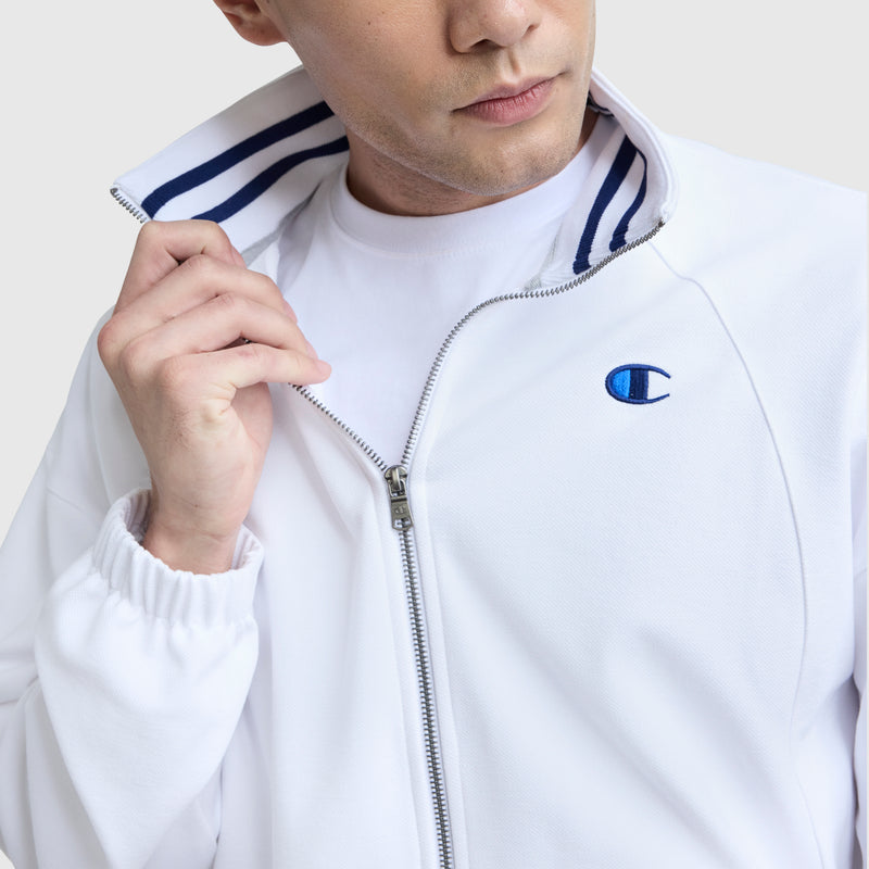 A person wearing the Champion Gameday Full Zip Mock Neck jacket with a blue striped collar and blue C logo over a white shirt, partially unzipped, stands against a plain background.
