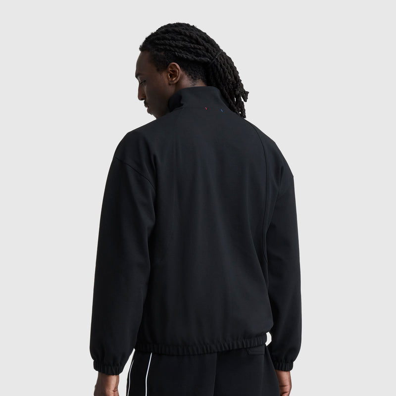 A person with long, dark, braided hair is seen from behind wearing the Champion Gameday Full Zip Mock Neck with C Logo and black pants against a plain light gray background.