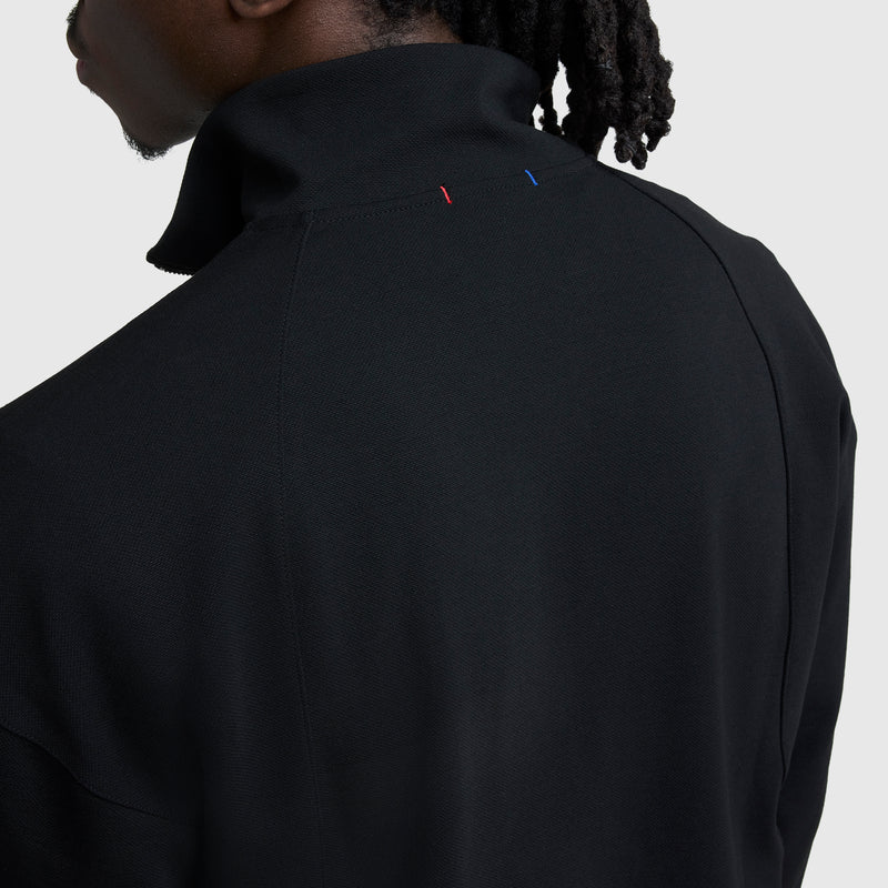 A person with braided hair is seen from behind wearing the Champion Gameday Full Zip Mock Neck jacket, featuring small red and blue C Logo stitches near the collar against a plain light background.