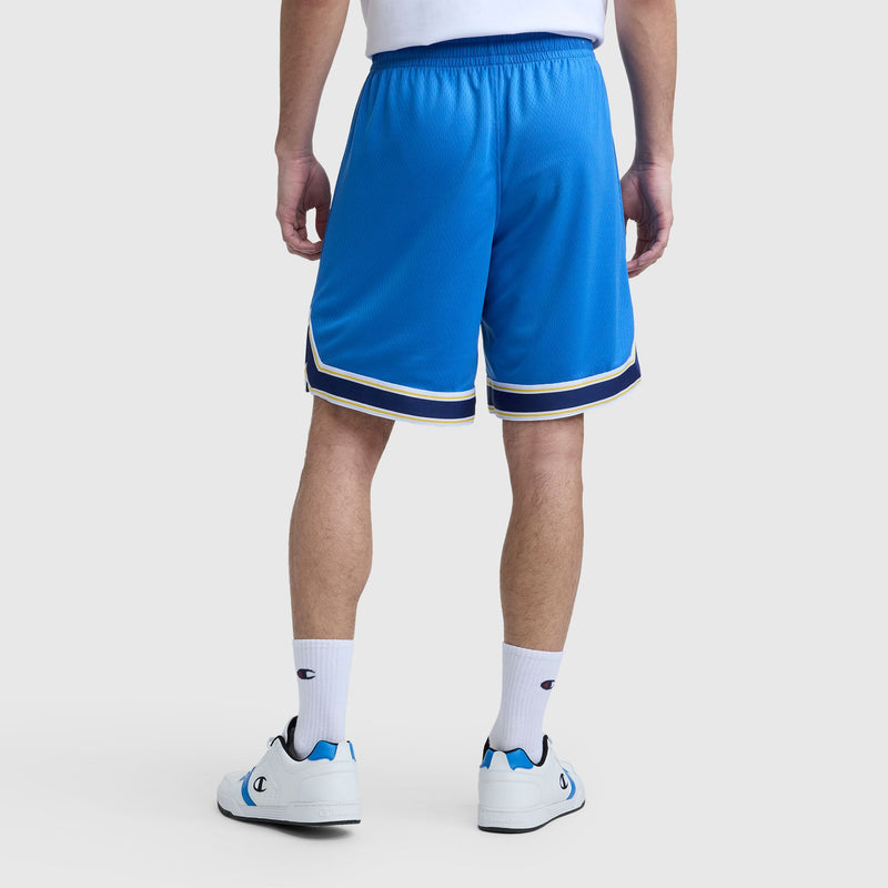 A person is shown from the back standing on a white background, wearing Champion's 10" Gridiron Reversible Short with Script Logo in bright blue with navy and white trim, paired with a white shirt, socks, and sneakers.