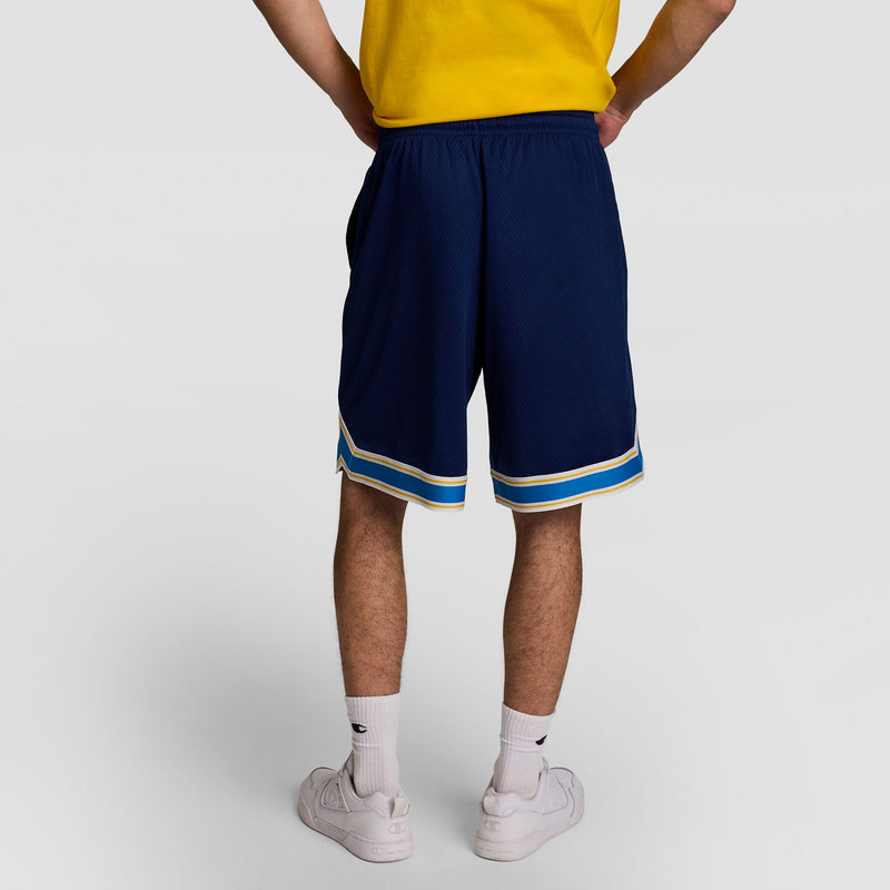 A person faces away, wearing a yellow shirt, Champion 10" Gridiron Reversible Short with script logo in dark blue with white and blue trim, plus white crew socks and sneakers, set against a plain light background.