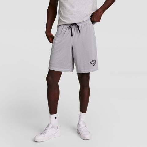 A person wearing a light gray T-shirt, light gray Champion athletic shorts with a drawstring, white socks, and white sneakers standing against a plain background.