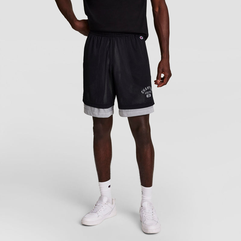 A person wearing a black T-shirt, black and gray Champion athletic shorts, white crew socks, and white sneakers stands against a plain light gray background.