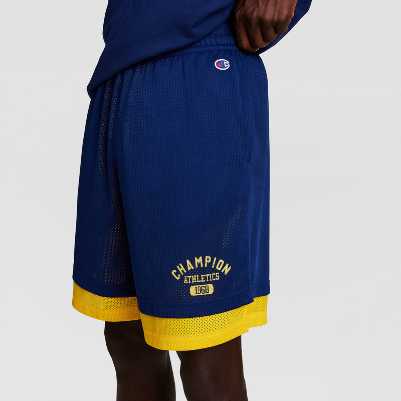 A person wears blue mesh athletic shorts with yellow trim and "CHAMPION ATHLETICS 1968" in yellow. The Champion logo is near the waistband. Shown from the waist down, paired with a Champion Powerblend Full-Zip Hoodie, C Logo - Big & Tall.