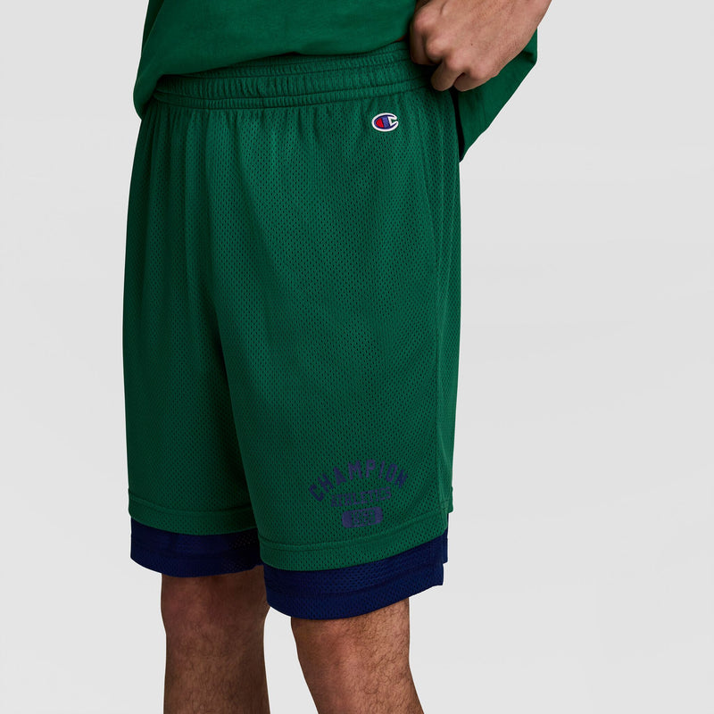 A person wearing Champion 8" Fleece Cargo Shorts, C Logo - Big & Tall in green is shown from the waist down against a plain background. The cotton-blend fleece ensures comfort for this sporty outfit.