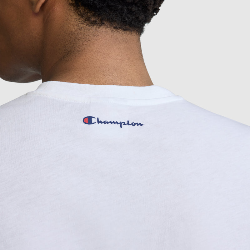 A back view of a person wearing the Champion Short Sleeve USA T-Shirt in white, featuring the blue and red Champion logo printed near the neckline, showcasing this stylish athletic tee.