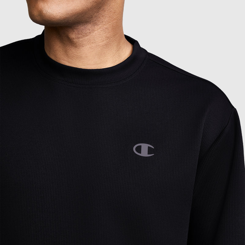 A person wearing a black Champion Sport Long Sleeve Crewneck, C Logo sweatshirt with the iconic Champion logo on the chest is shown from the shoulders up against a plain light background, effortlessly showcasing classic athletic wear style.