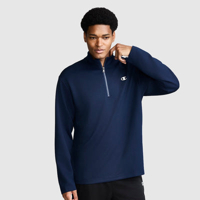 A man wearing a navy blue Champion quarter-zip long-sleeve pullover, posed against a light gray studio background.