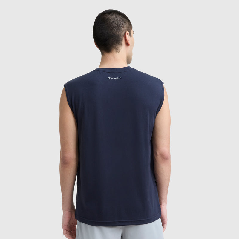 A person with short dark hair is seen from behind in a sleeveless navy blue Champion Sport Crewneck Muscle Tee, Script Logo, and light gray shorts against a plain background. The small Champion logo appears on the upper back of the tee.