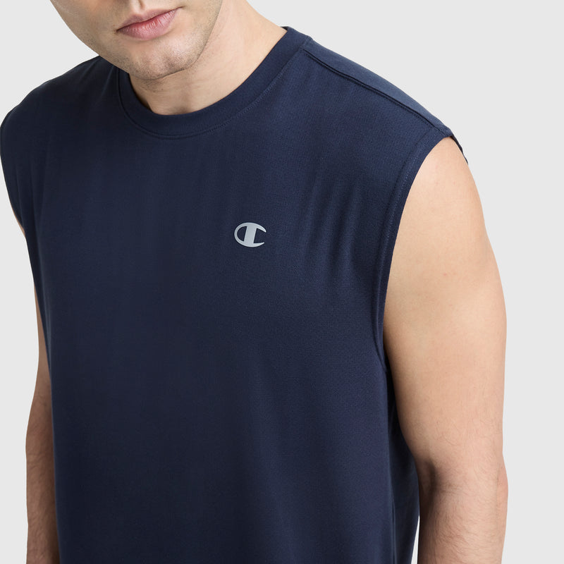 A person wearing a sleeveless navy Sport Crewneck Muscle Tee by Champion, featuring the script logo on the left chest, stands against a plain light background.