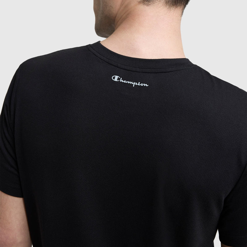 A man wears a black Champion Sport Crewneck T-Shirt featuring the white script logo on the upper back, shown from behind against a plain background.