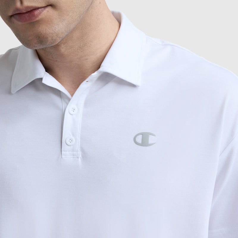 A person wears a white Champion Sport Polo, featuring three buttons and a small silver C logo on the left chest. The image highlights its athletic style, focusing on the upper torso and part of the face against a plain background.