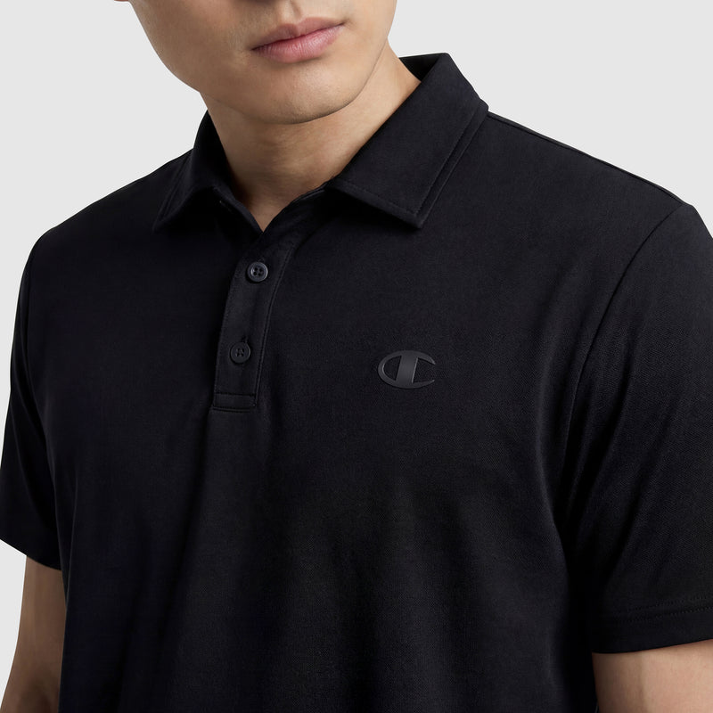A person wears a black Champion Sport Polo, C Logo, featuring buttons and a subtle embroidered logo on the left chest, shown from shoulders to just above the mouth against a light background for an athletic look.