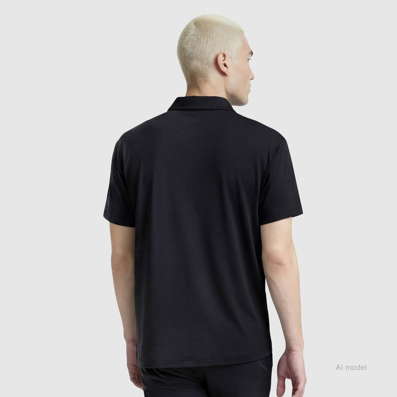 A person with short, light blonde hair is shown from the back wearing a black Champion Sport Polo with C Logo and black pants, standing against a plain light gray background.