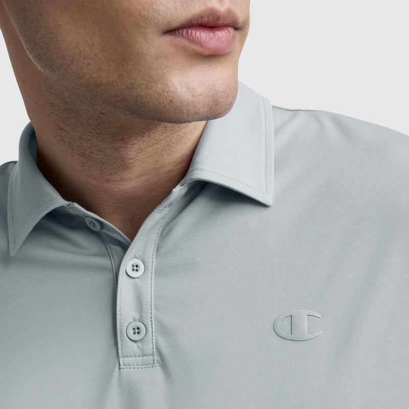 A close-up of a person in the Champion Sport Polo, C Logo—a light gray athletic shirt with buttons and the Champion logo stitched on the chest. Only the lower half of their face is visible.