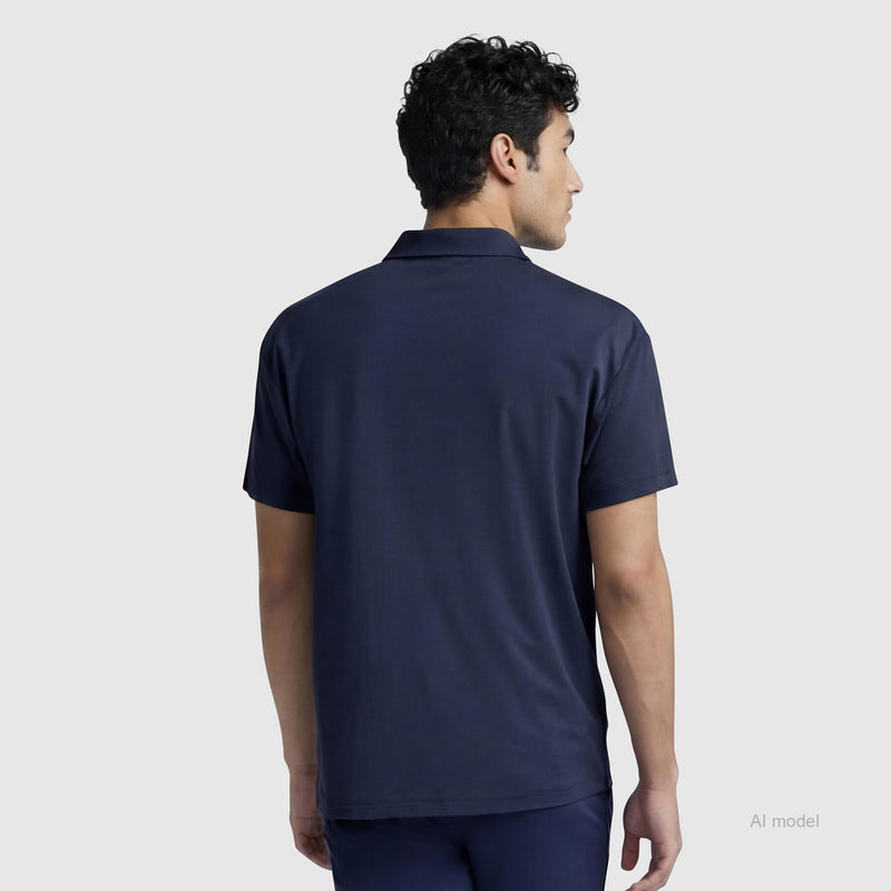 A man with short curly hair, seen from behind against a light gray background, is wearing a Champion Sport Polo with C Logo and matching pants in navy blue.
