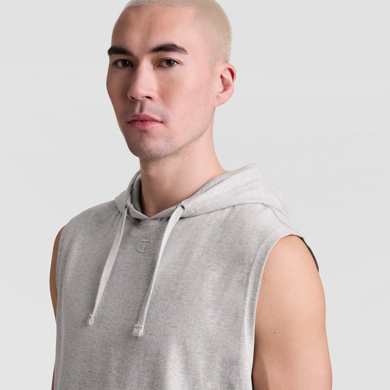 A person with short, light blond hair wears a Champion Sleeveless Hoodie with an Embroidered C Logo and looks toward the camera against a plain light gray background.