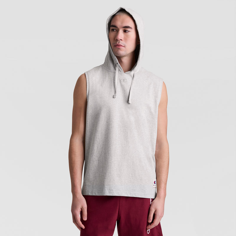A person wears a Champion Sleeveless Hoodie with an embroidered C logo, hood up, and maroon shorts, standing facing forward against a plain light background.