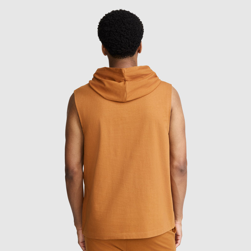 A person is standing with their back to the camera against a plain light gray background, wearing the Champion Jersey Sleeveless Hoodie, C Logo in orange—crafted from soft ring-spun cotton—and matching pants.