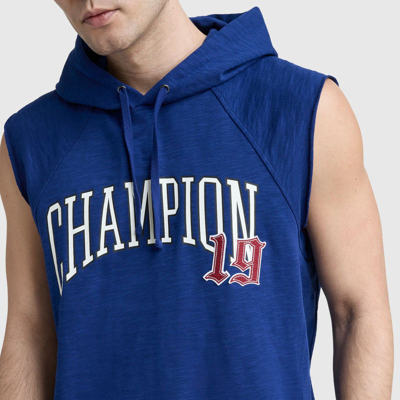 A person wearing Champion’s Modern Retro Washed Sleeveless Hoodie, featuring heavyweight blue cotton, a hood with drawstrings, vintage gym-style CHAMPION lettering and “19” in white and red. Only the lower face and upper body are shown.